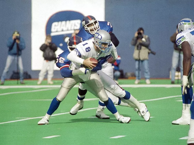 Seattle Seahawks quarter back Stan Gelbaugh (18) gets sacked by Lawrence Taylor